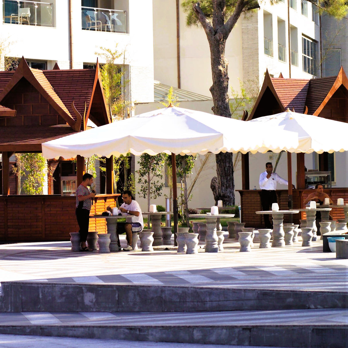 Cenadores de madera para exteriores con mesas y taburetes de mármol. Obras de acondicionamiento en Antalya, Turquía. Espacios de comedor de inspiración asiática.